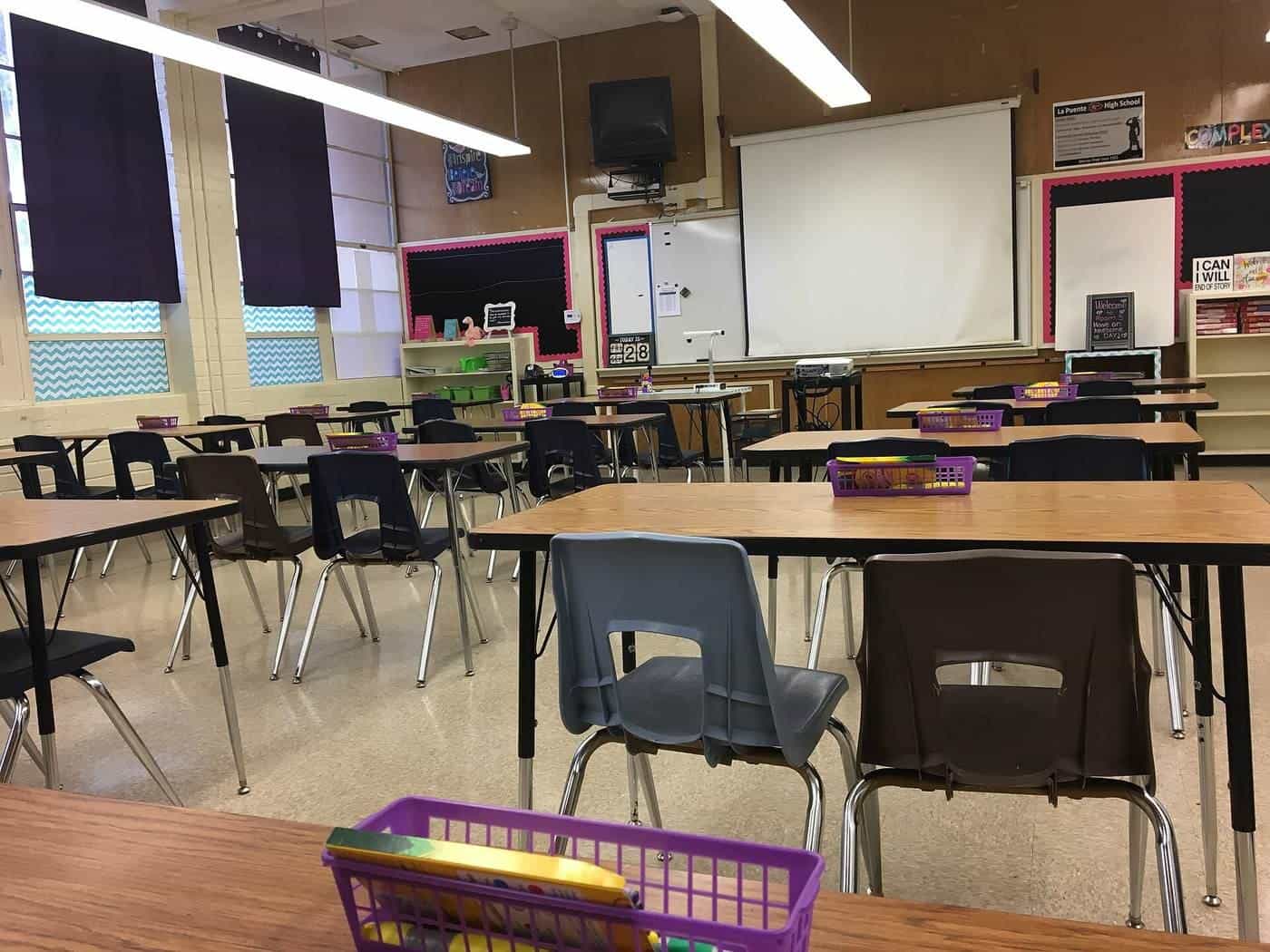 An empty modern classroom with desks, chairs and a projector screen