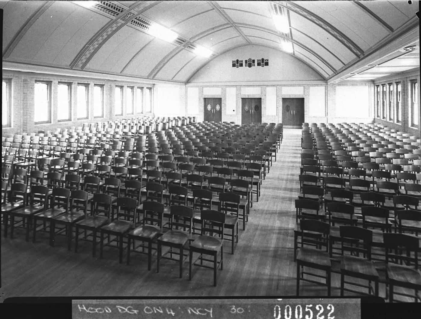 A large historic school assembly hall with rows of chairs