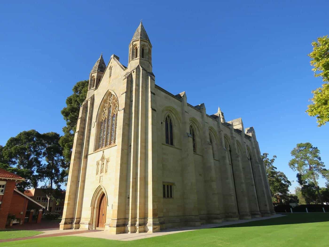 A sandstone Gothic-style school chapel under a blue sky