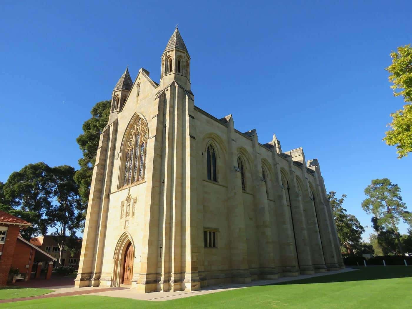 A sandstone Gothic-style school chapel under a blue sky
