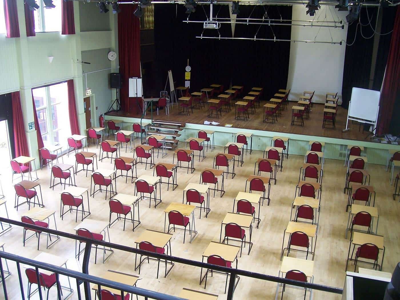Rows of empty desks set out for an exam in a school hall